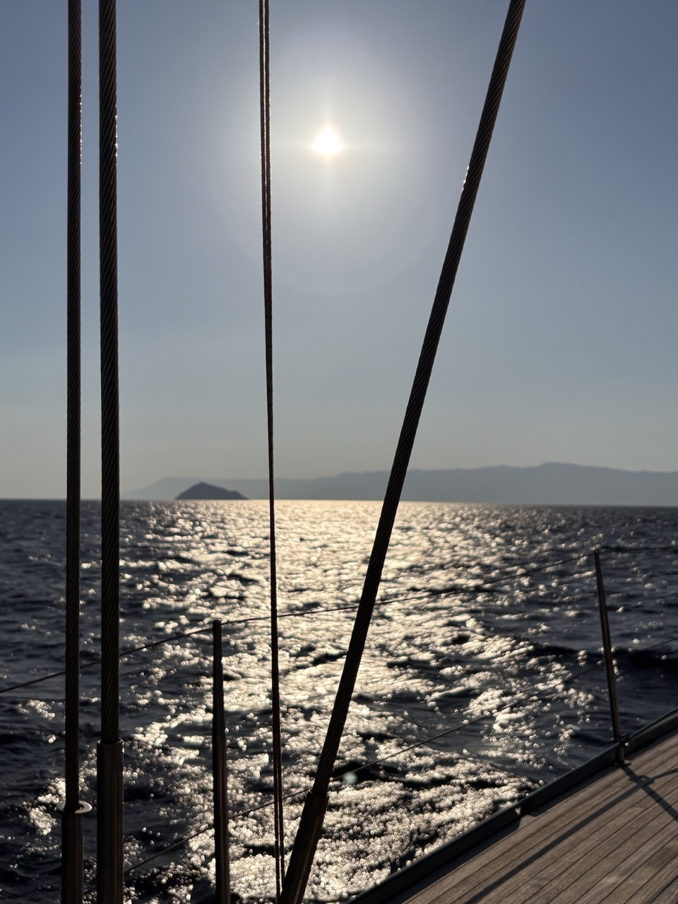 Afternoon sun glittering on a calm sea, seen through the shrouds