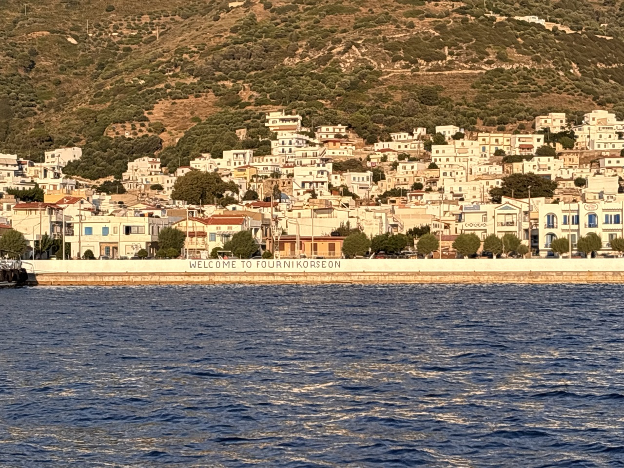 The harbour front of Fournoi — “Welcome to Fourni Korseon” painted along the quay
