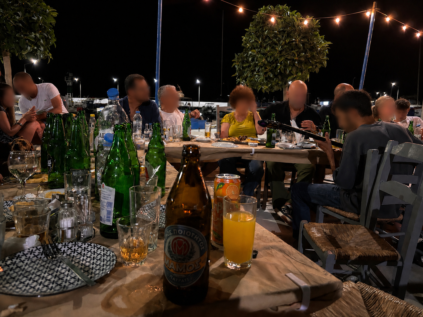 The taverna table towards midnight — bottles, bouzouki and rebetiko under string lights
