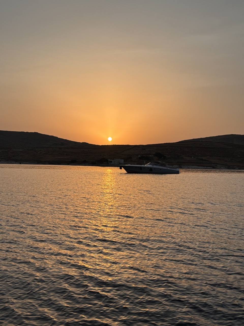 The sun dropping behind the hills of our anchorage across Mykonos